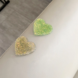 Close-up of glittery heart-shaped phone grips in light green and gold pink colors