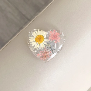 Close-up of heart-shaped resin phone grip featuring real dried flowers and silver foil