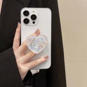 Macro shot of heart-shaped glitter phone grip with iridescent sequins on a white smartphone