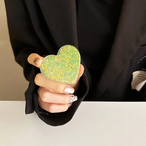 Detail of green glitter heart phone grip holder with shiny sequins on a smartphone