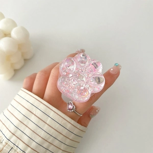 Close-up of pink translucent cat paw phone grip with colorful sequins and heart glitter