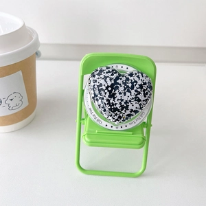Magnetic heart phone grip with black and white ink splatter texture on a mini green chair