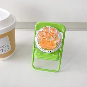 Détail d'un support de téléphone patte de chat laser coloré sur une mini chaise verte
