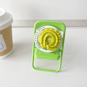 Detail of green mini folding chair phone stand with a decorative flower container on top