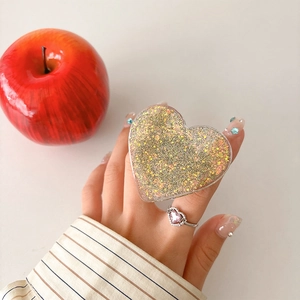 Macro detail of heart-shaped glitter phone grip with gold and silver sparkles