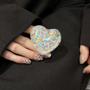 Macro detail of a transparent heart-shaped phone grip with colorful glitter and sequins