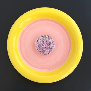 Close-up of heart-shaped glitter phone grip with pink and purple sequins on a pink plate