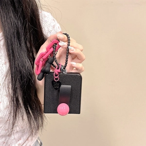 Dettaglio custodia in pelle nera con chiusura a sfera rosa e catena con cuore