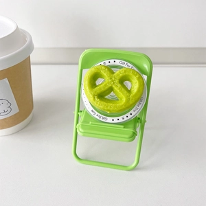 Detailed view of a green pretzel-shaped phone griptok on a transparent base
