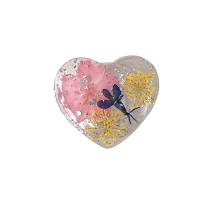 Heart-shaped resin phone grip with pink dried flowers and silver foil on white background
