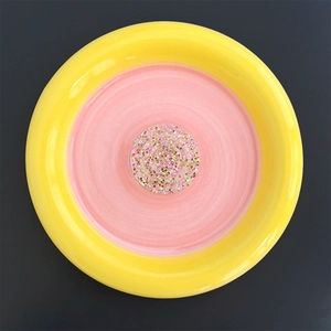 Top view of a round yellow phone grip with glitter sequins and pink swirl resin detail