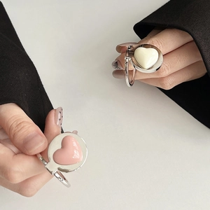 Detailed view of silver heart-shaped phone ring holder with pink and white glaze finish