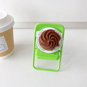 Detail of creative green folding chair phone stand with chocolate cream decor