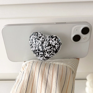 Heart-shaped phone grip with black and white ink splatter texture on a white smartphone