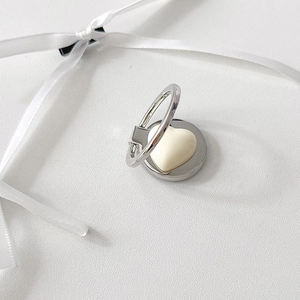 Close-up of heart-shaped silver phone ring stand with creamy white inlay on silk