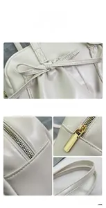 Macro detail of creamy white bow tote showing gold zipper and precision stitching