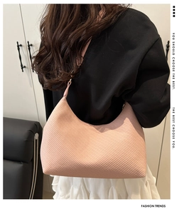 Close-up of light pink textured crescent bag worn on shoulder by a model