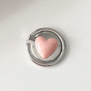 Close-up of a pink heart-shaped phone ring holder with a polished silver metal base