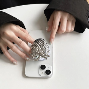 Macro shot of silver metallic strawberry-shaped magnetic phone grip on a white smartphone