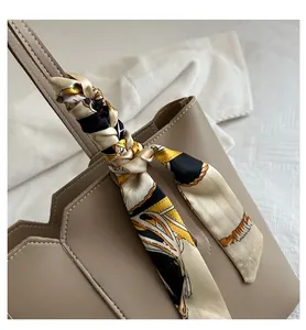 Detail of minimalist tote bag with geometric fold design and silk scarf accessory