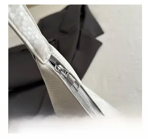 Close-up of smooth silver metal zipper on white snakeskin textured crossbody dumpling bag