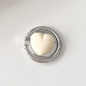 Macro detail of heart-shaped phone ring holder with cream heart and silver metal frame