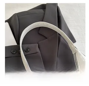 Close-up of white embossed snake texture shoulder bag with curved handle and silver zipper