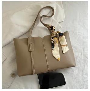 Detail view of large beige tote bag featuring silk scarf handle and size comparison with phone