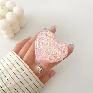 Detailed view of a glittering pink heart-shaped expanding cell phone grip and stand