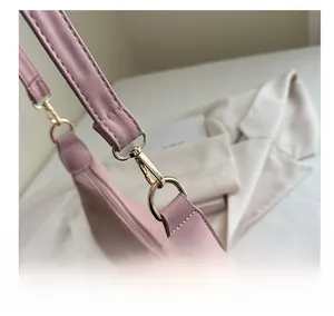 Detailed close-up of the bright gold metal hook on a light pink faux leather tote bag