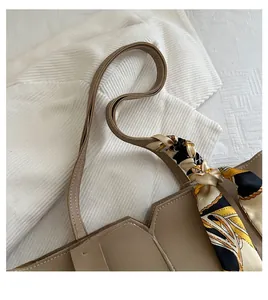 Detail of beige tote bag handle wrapped with a stylish patterned silk scarf decoration