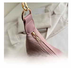 Close-up of smooth gold metal zipper and pink woven texture on large shoulder bag