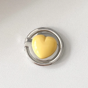 Detail view of a 3D yellow heart phone ring holder with a polished silver metallic base