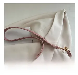 Detail of pink knitted bag featuring light pink faux leather strap and golden metal clasp