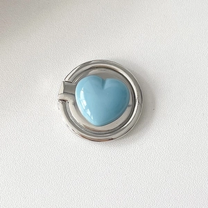 Macro detail of foldable silver heart ring phone holder with blue enamel finish