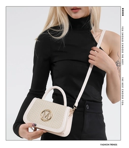 Detail of a beige patchwork crossbody bag with woven texture and a metallic M logo
