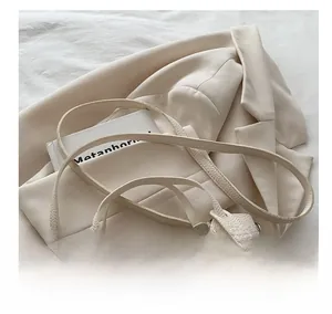 Detail of adjustable litchi texture straps and metal buckles on a cream bucket bag