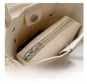 Interior detail of beige bucket bag showing smooth zipper pouch and lychee texture