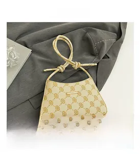 Borsa a mezzaluna beige monogramma con manico a nodo su un blazer grigio