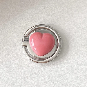 Close-up of pink heart-shaped phone ring holder with silver metal on leather background