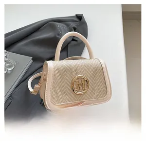 Detail of a beige leather handbag featuring woven texture and a gold metal letter M