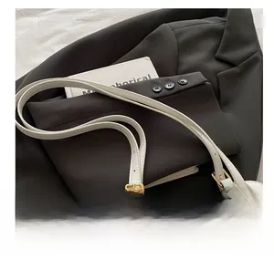Close-up of cream canvas and white leather shell bag with elegant gold metal buckle