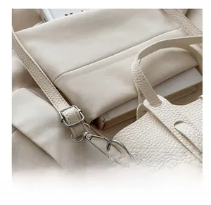 Detail of adjustable metal buckle and textured leather strap on a beige crossbody bag