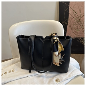 Detail of black tote bag with white contrast stitching and decorative printed silk scarf