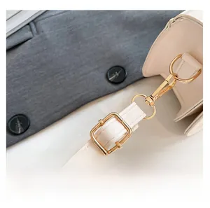 Detail of cream leather shoulder strap with adjustable light gold metal buckle hardware