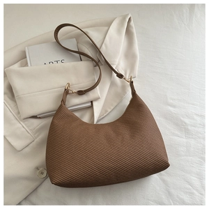 Détail de la texture tressée marron du grand sac cabas avec boucle en métal doré