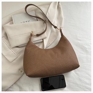 Vue détaillée de la texture tissée marron du grand sac porté épaule avec boucles dorées