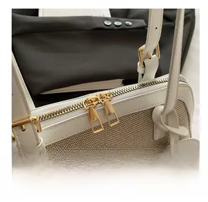Detail of smooth gold-tone zipper on beige canvas shell bag with fashion pendant