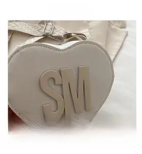Close-up of heart-shaped crossbody bag featuring 3D SM letters and woven strap