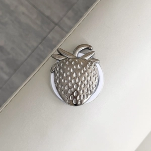 Macro shot of silver metallic strawberry-shaped magnetic phone grip with seed texture details